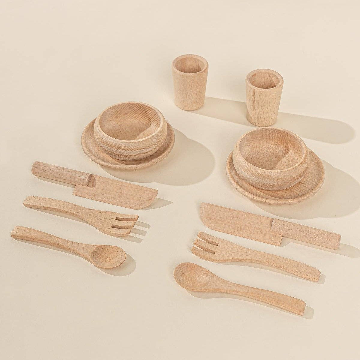 Set of wooden tableware including bowls, cups, knives, forks, and spoons.