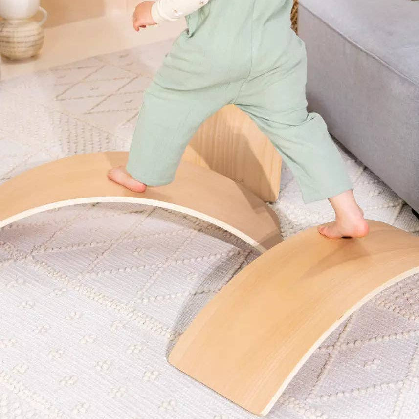 Person using a wooden balance board on a carpeted floor
