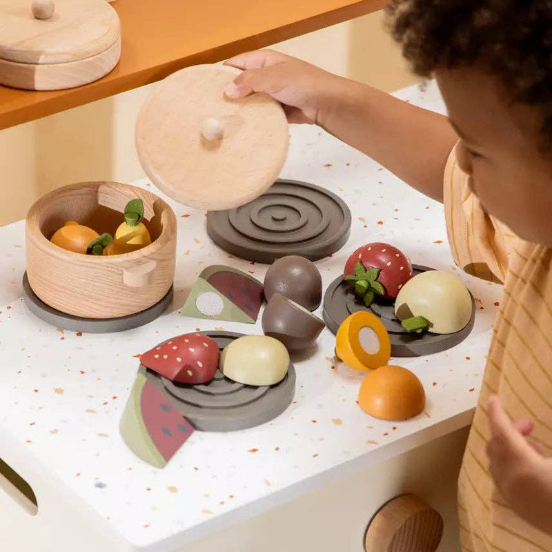 Child playing with wooden toy kitchen set