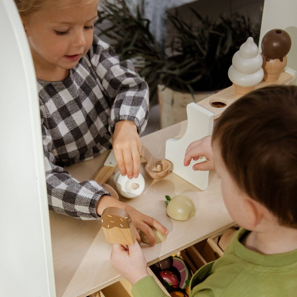 Two children playing with wooden toys on a table.