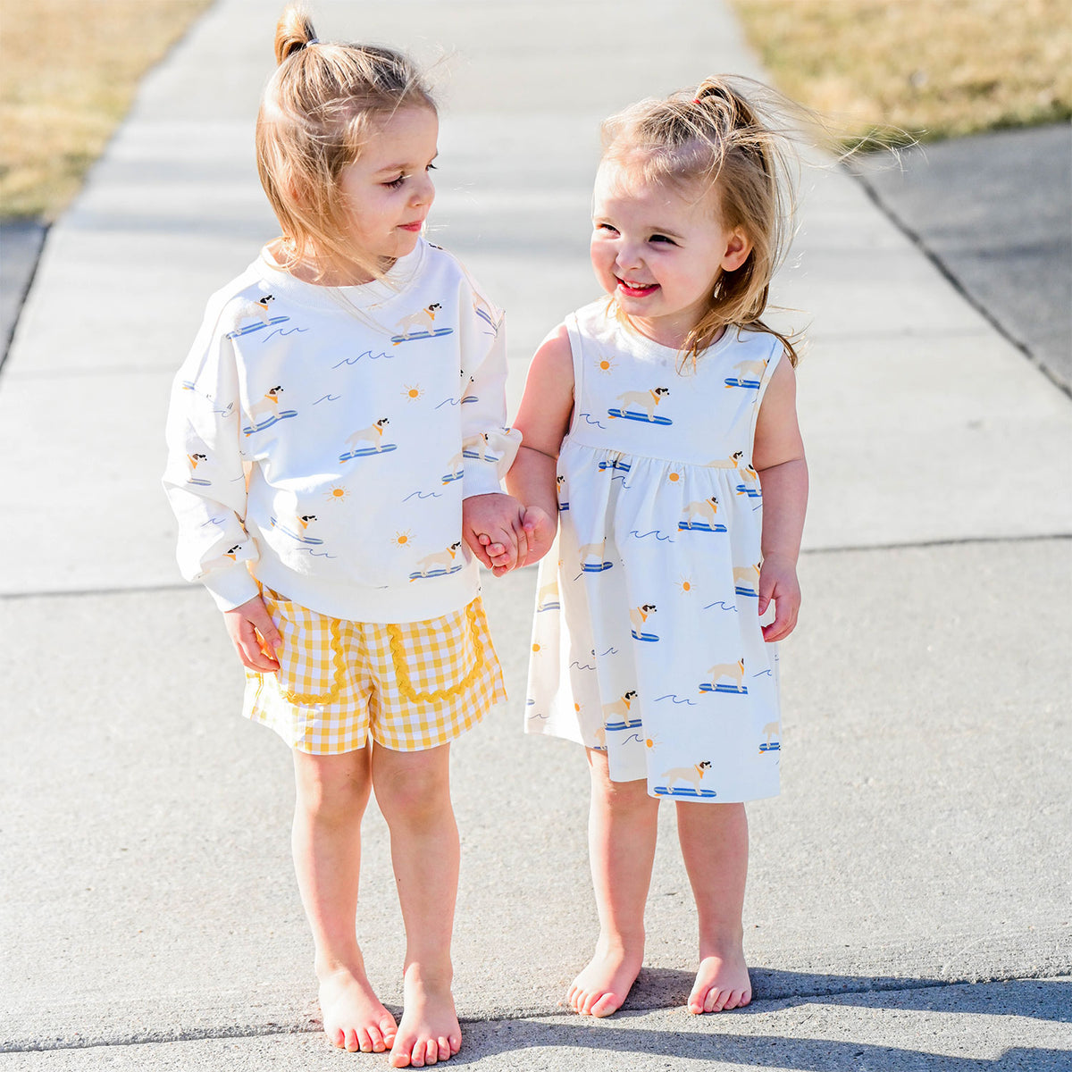 surfing dogs sweatshirt with lemon check libby shorts and surfing dogs tank dress - lifestyle of girls holding hands